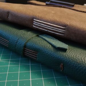 2 leather journals (green and brown) on a green mat.